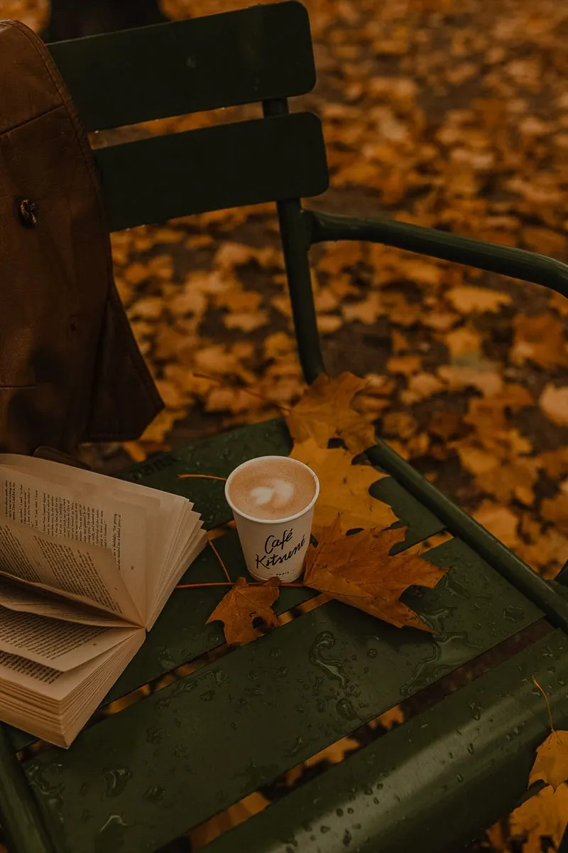 Un libro abierto y una taza de café entre hojas de otoño